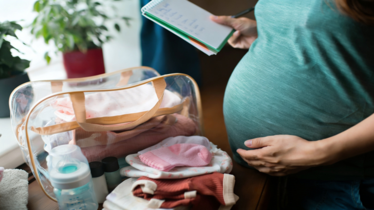 Schwangere Frau packt die Kliniktasche mit Babysachen und Checkliste