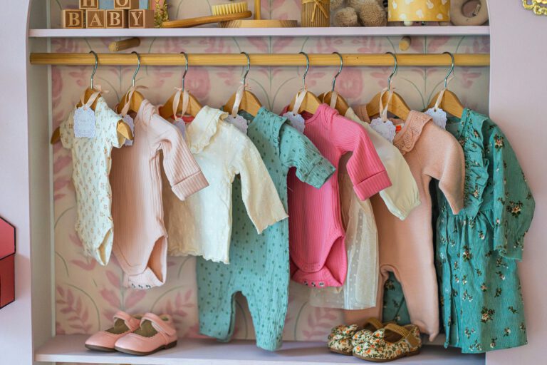 Bunte Babykleidung hängt ordentlich aufgereiht in einem hellen Kinderzimmerschrank