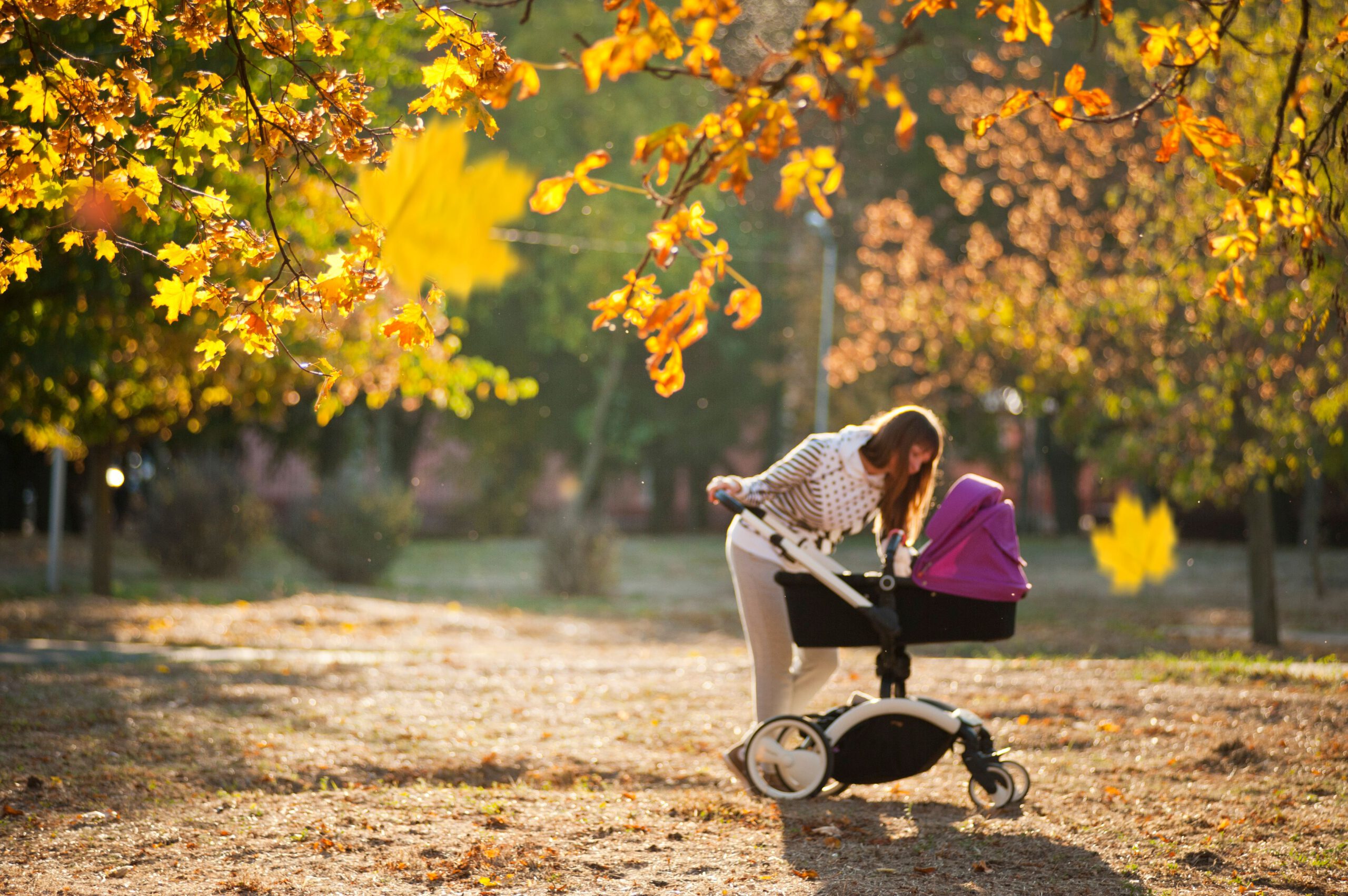 Mutter mit Kinderwagen im Herbstpark